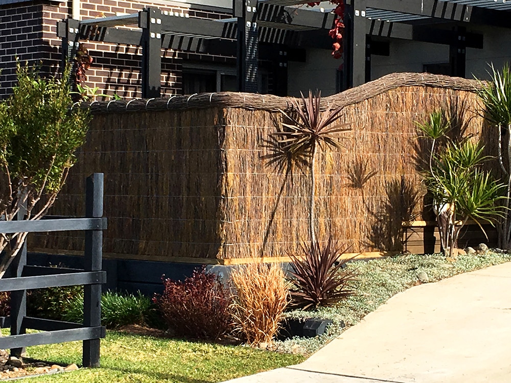Brushwood fence that curves around a residential home